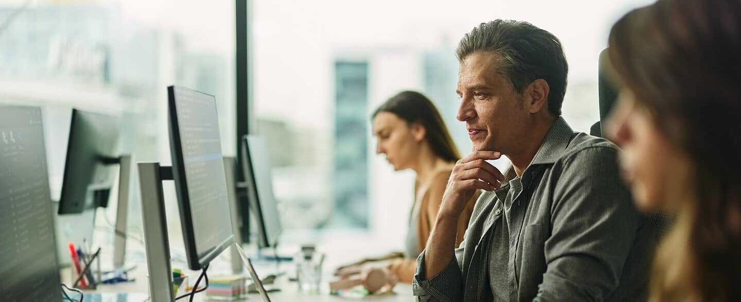 Smiling web designer working on PC and laptop in the office.